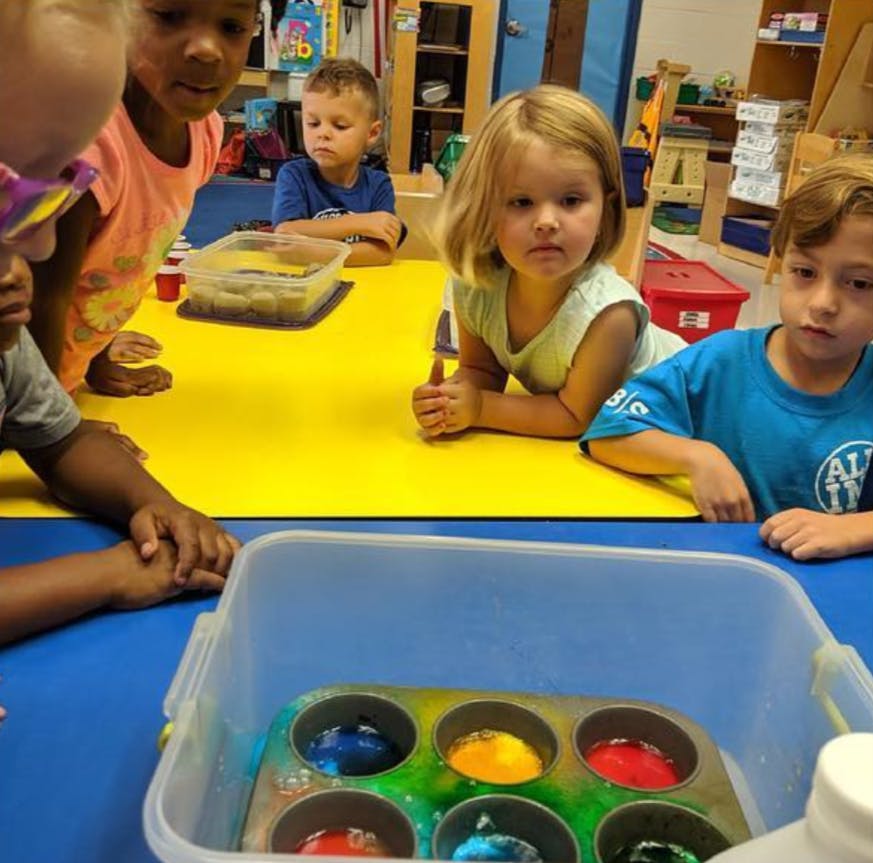 Children at a table with a container of colorful liquids