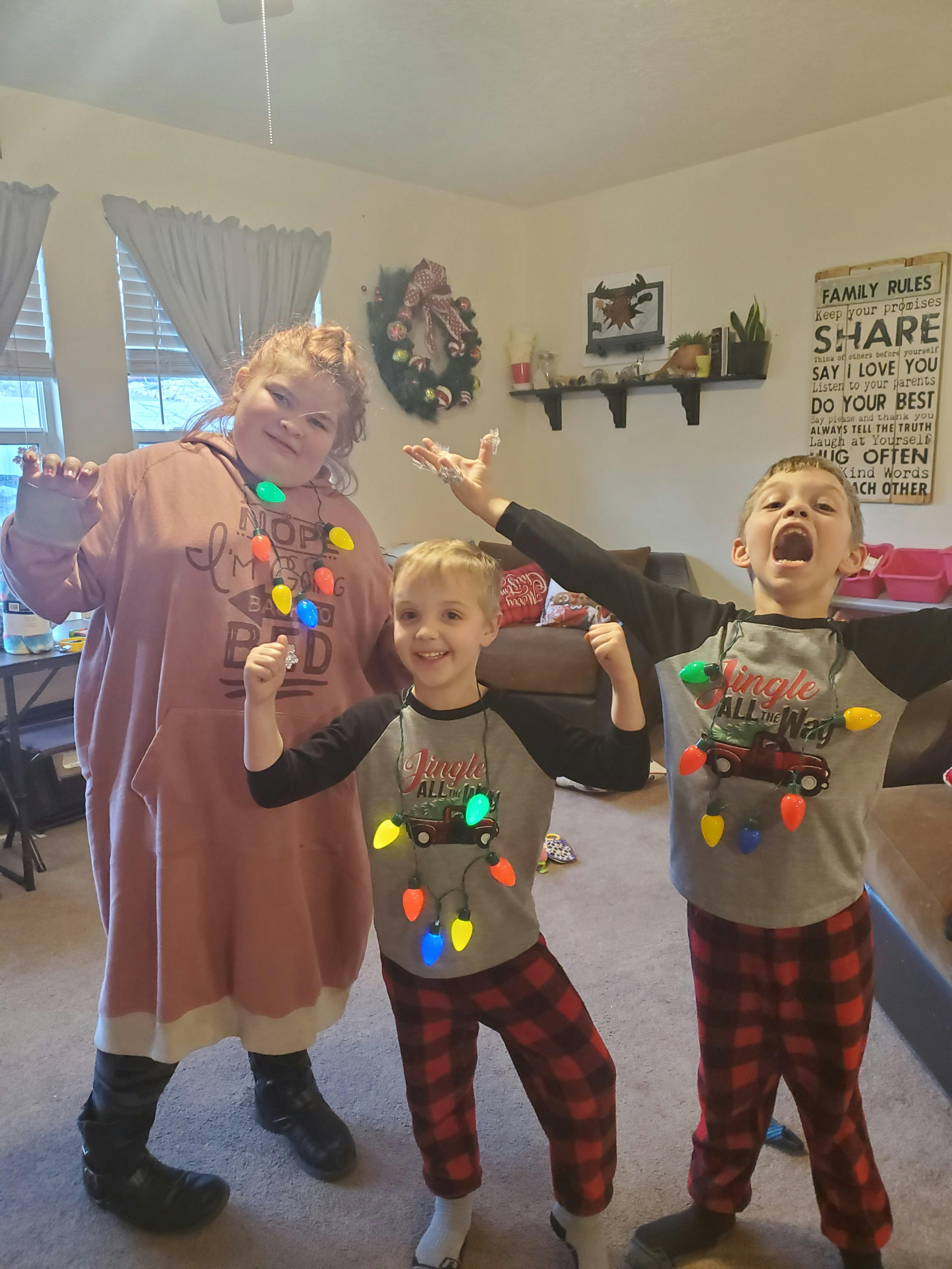 Three children wearing Christmas light necklaces