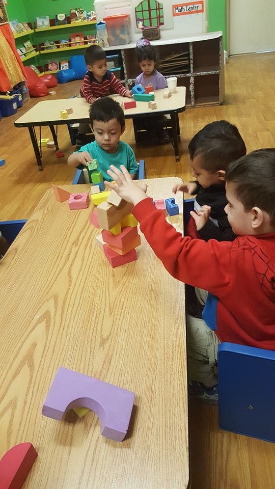 Children playing with blocks at tables in a classroom