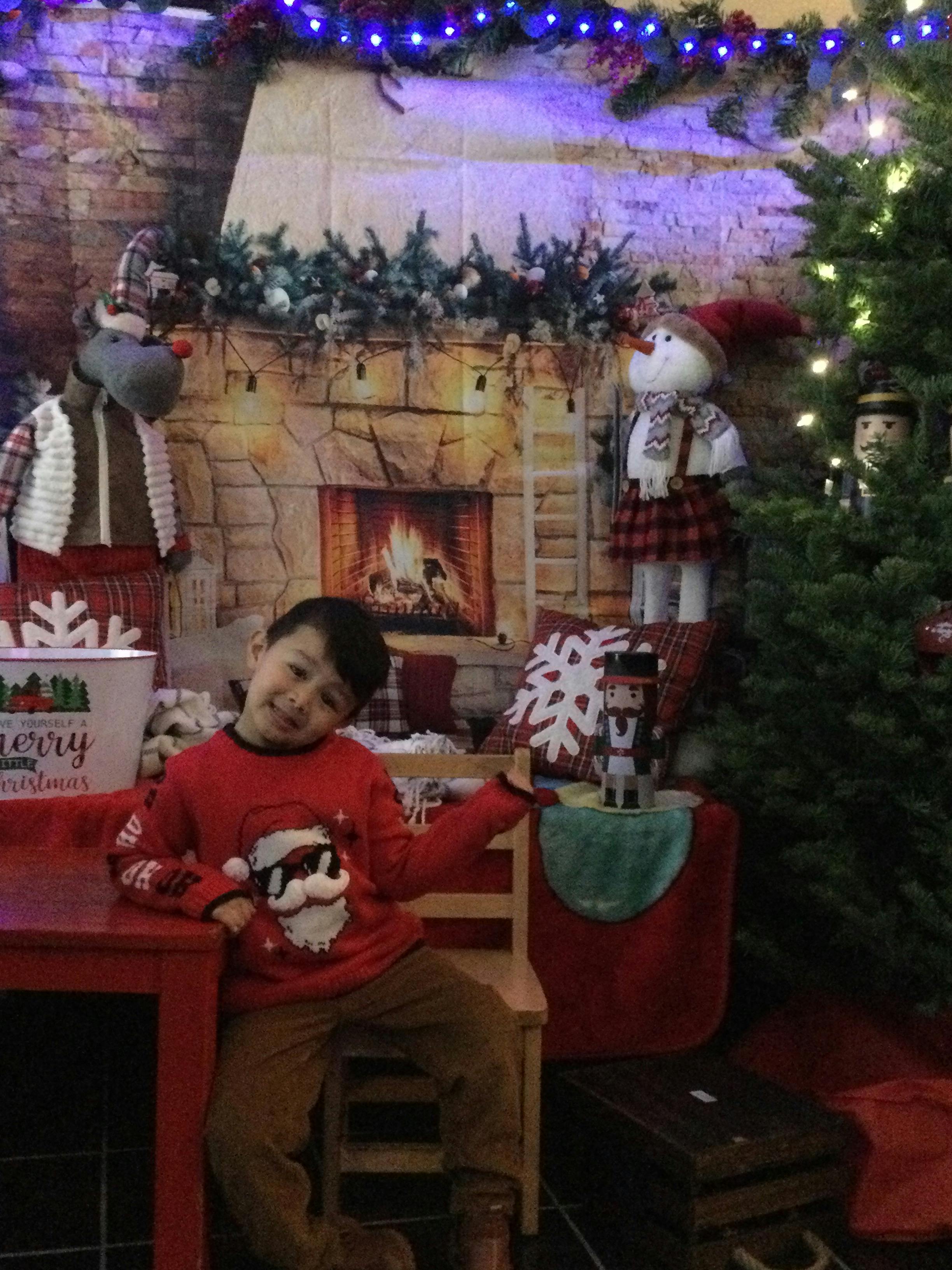 Child in a Santa sweater sitting in a holiday-decorated room