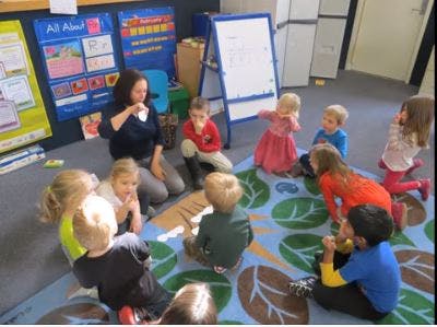 Adult and children sitting on a rug in a classroom
