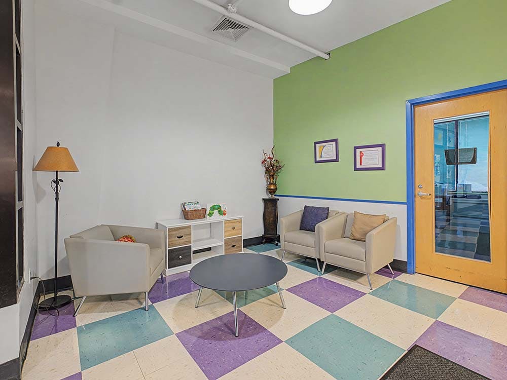 Lounge area with three armchairs, a coffee table, and a colorful checkered floor