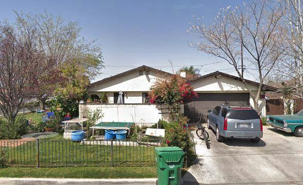 House with a car in the driveway and a green trash can in front