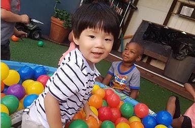 Child in a ball pit with another child in the background