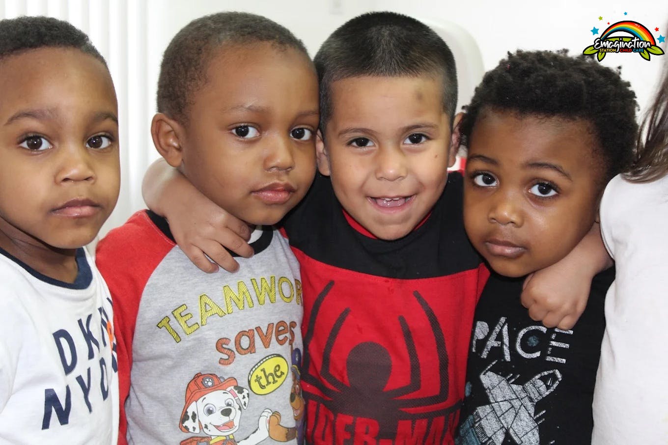 Four children standing together, one with arm around another