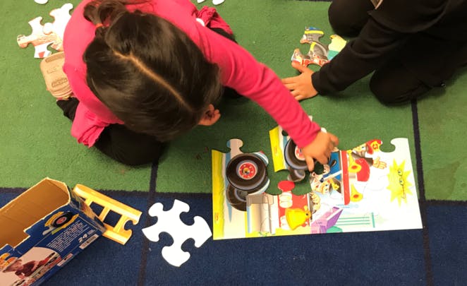 Two children assembling a floor puzzle