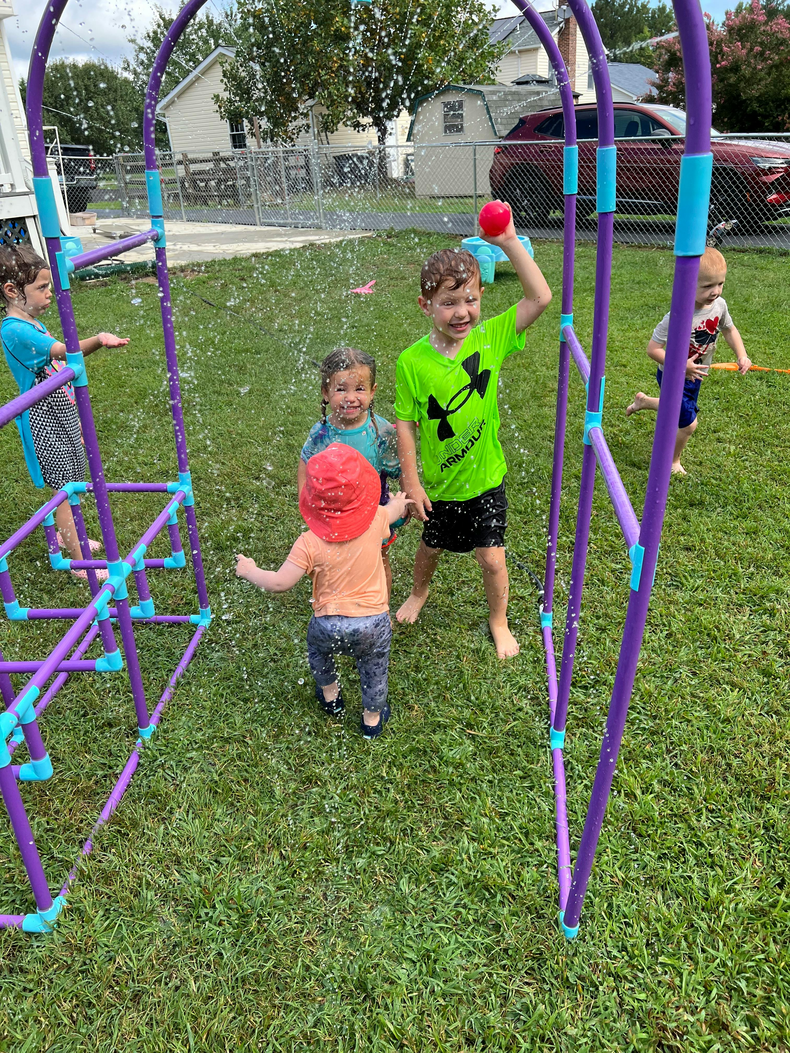 Children playing in a sprinkler on a grassy lawn