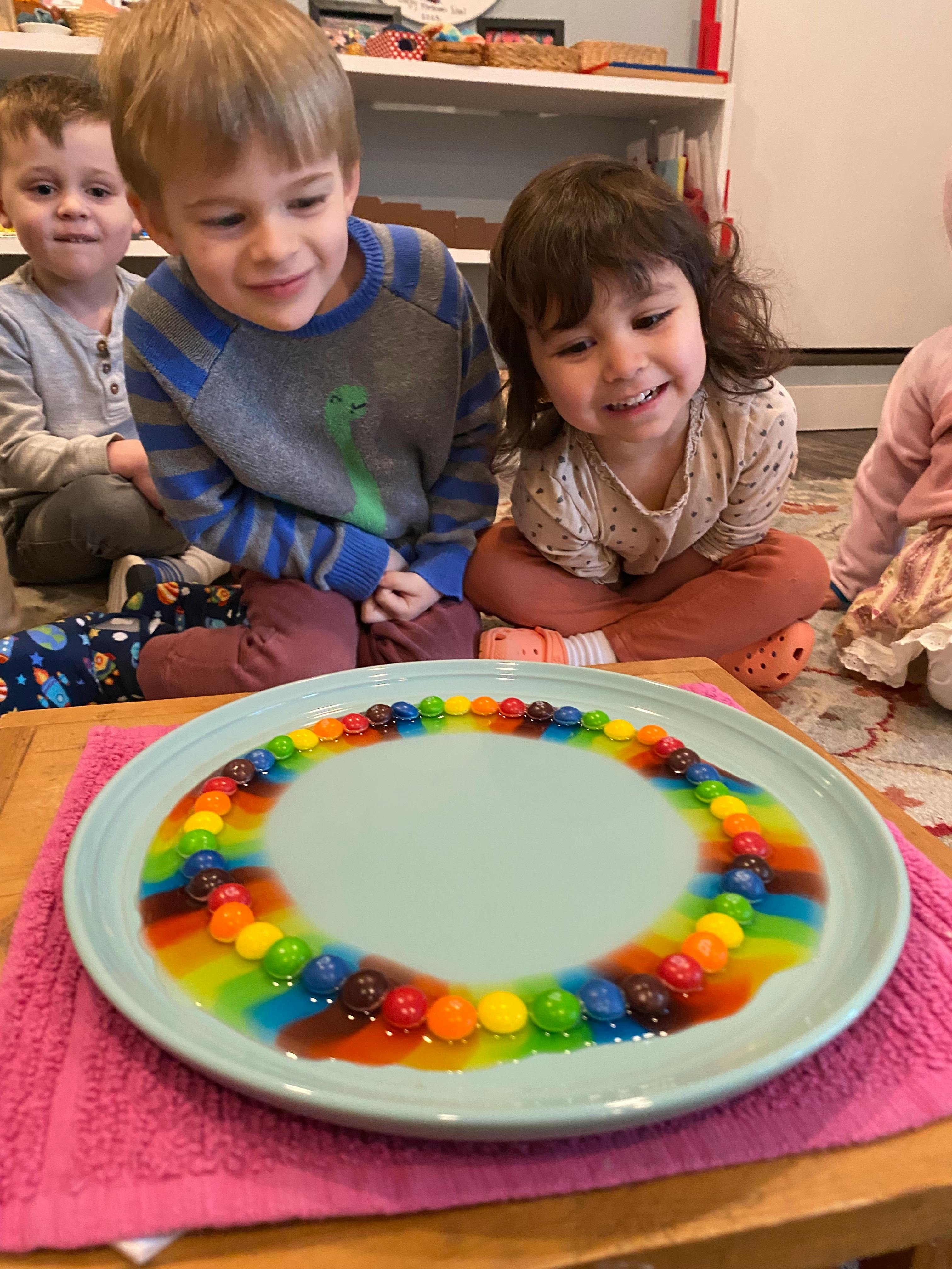 Children observing candies dissolving on a plate