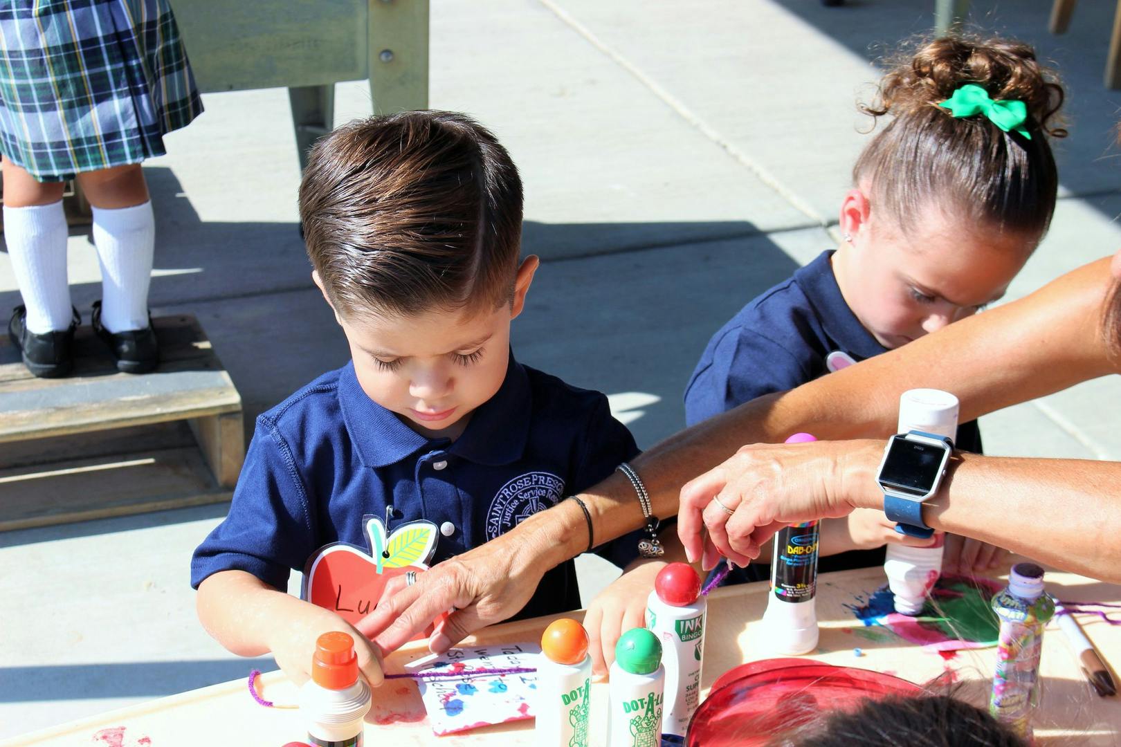 Two children and an adult doing an art activity with paint bottles