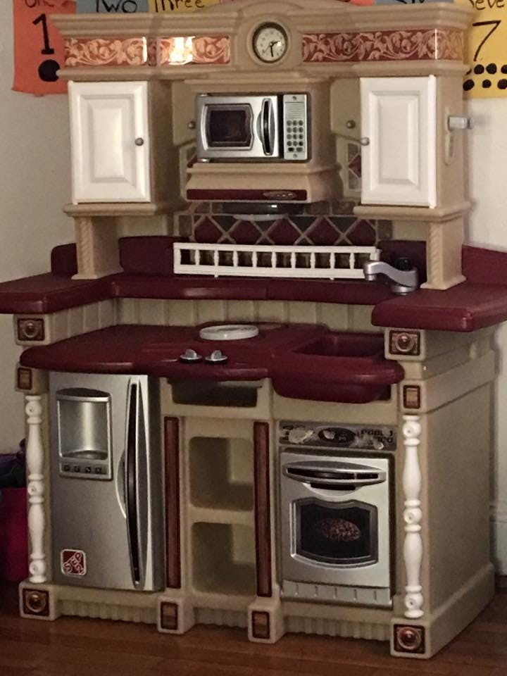 Child's play kitchen with refrigerator, oven, microwave, and sink