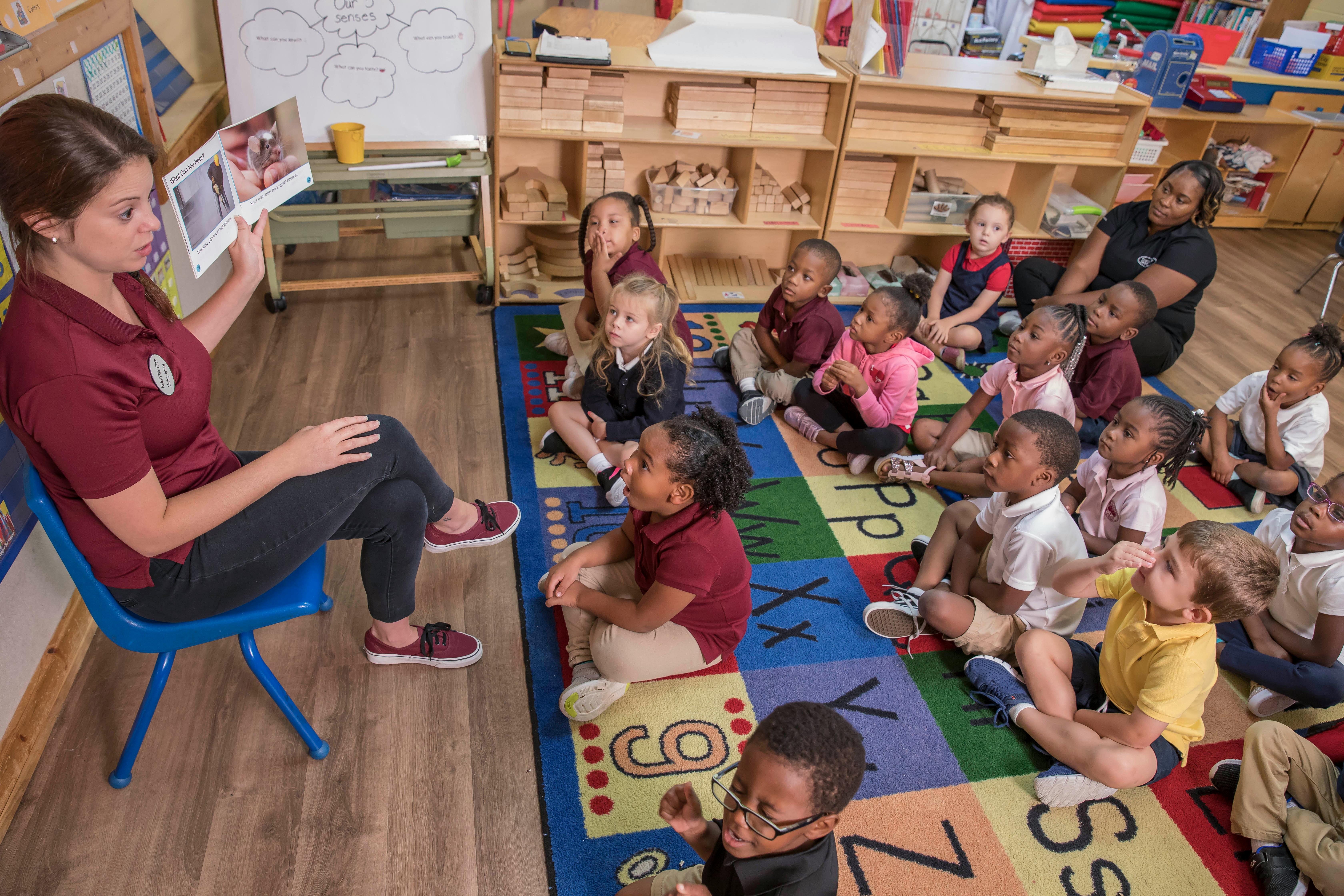 Person reading a book to a group of children in a classroom
