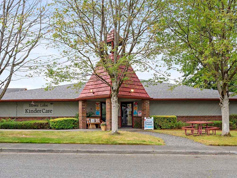Silver Lake KinderCare building with a red roof, green bushes, and picnic tables