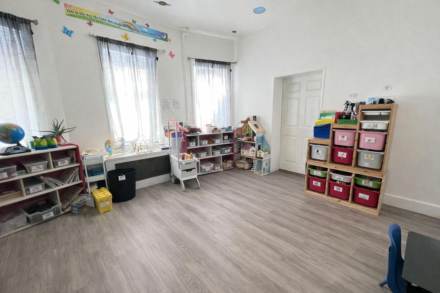 Classroom with shelves and bins for toy storage and a dollhouse