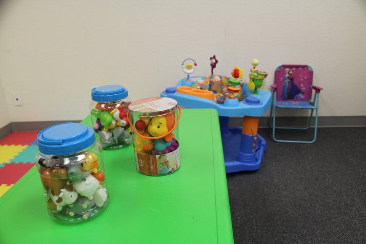 Jars of toys on a green table next to a blue activity table and chair