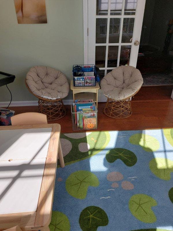 Two papasan chairs with a small table holding books and baskets between them