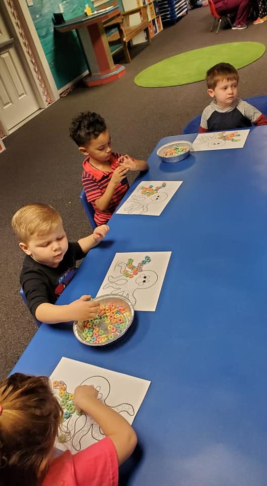 Children at a table doing a craft with cereal