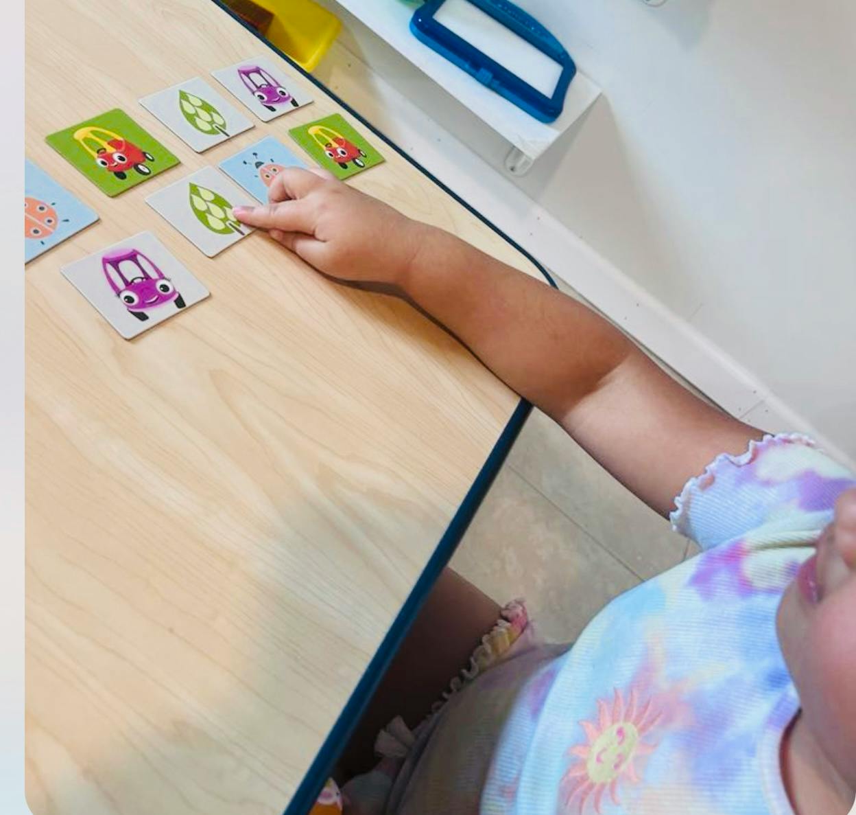 Child's hand pointing at a card on a table