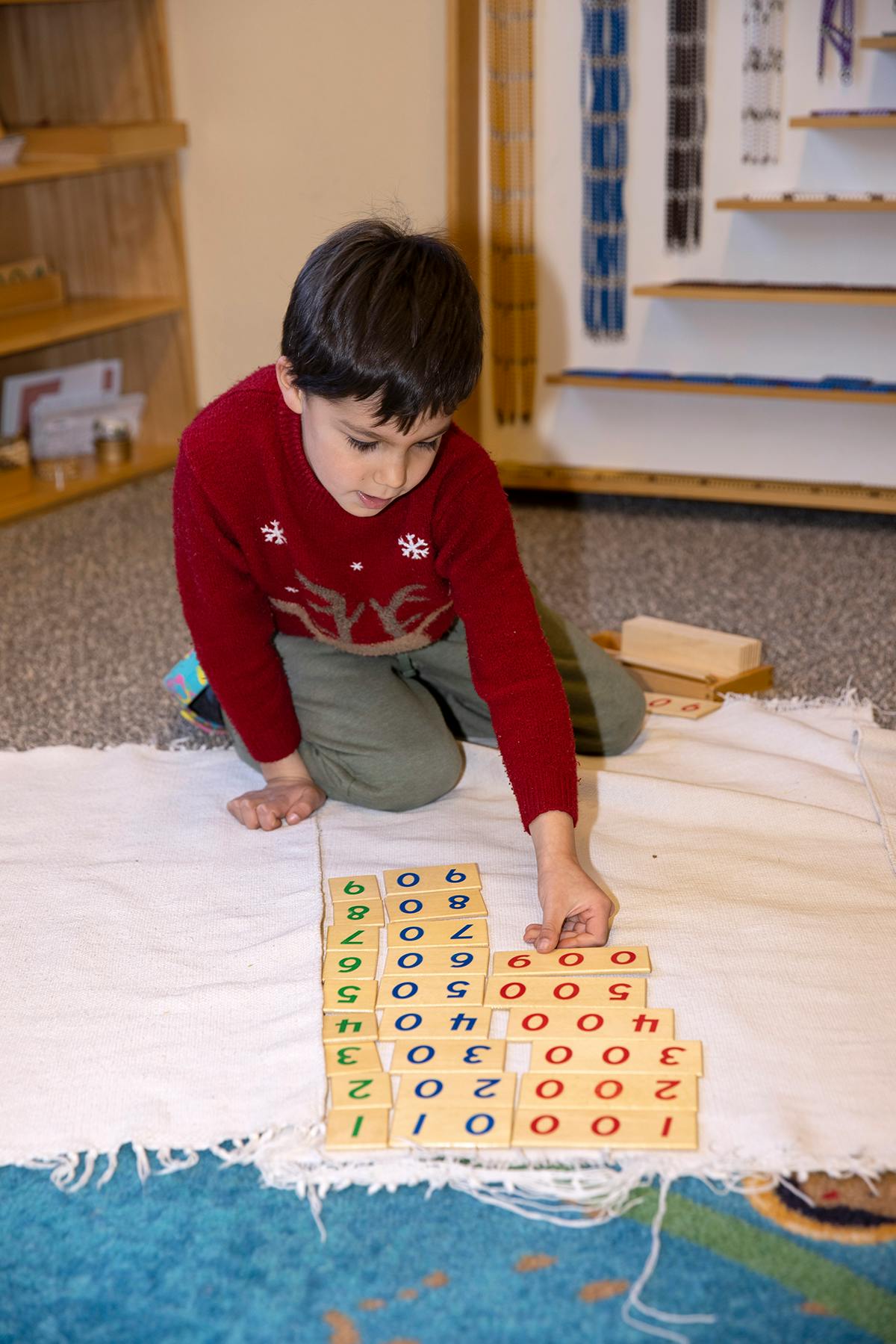 Child kneeling and arranging number blocks on a white mat