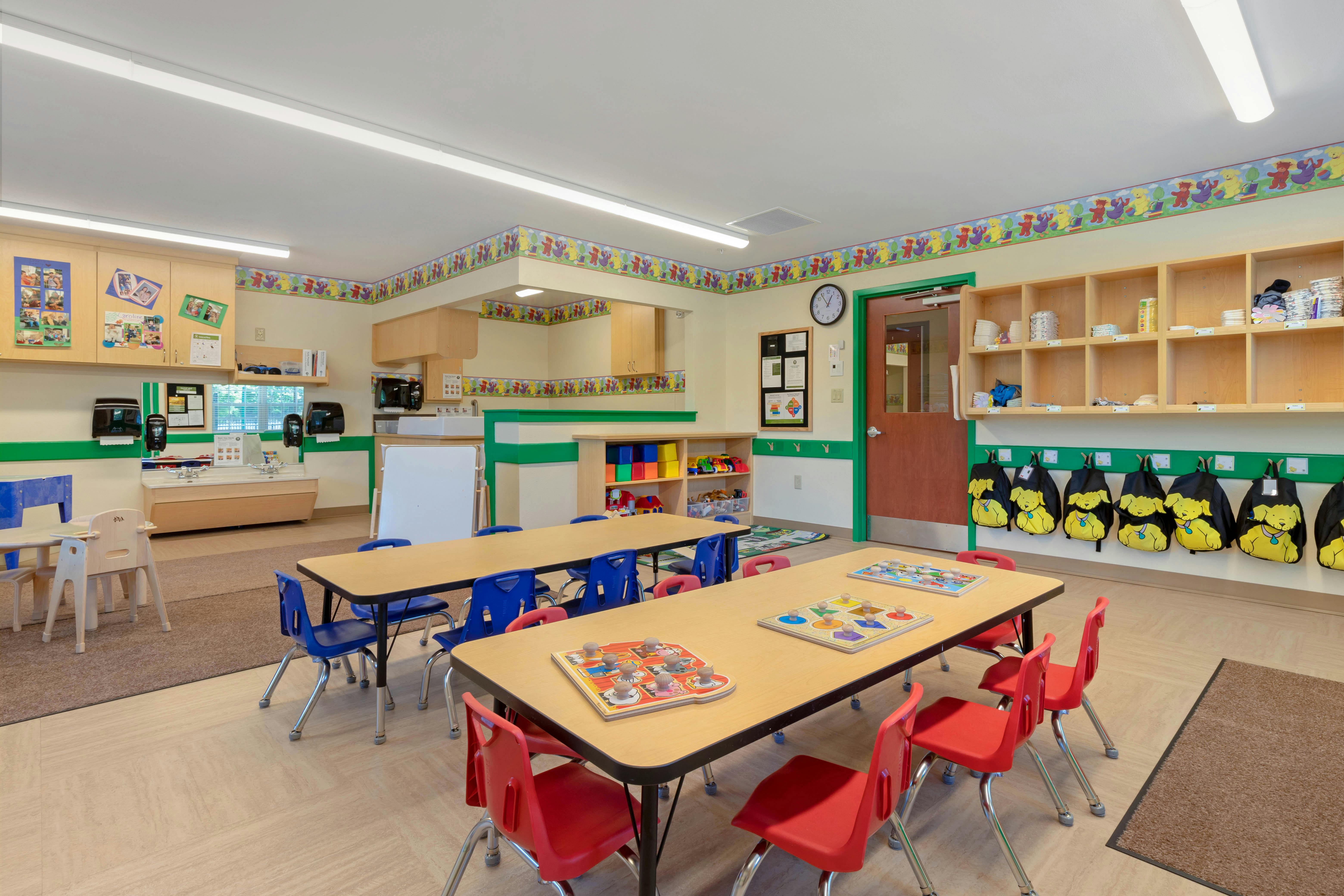 Classroom with tables, chairs, educational toys, and colorful wallpaper
