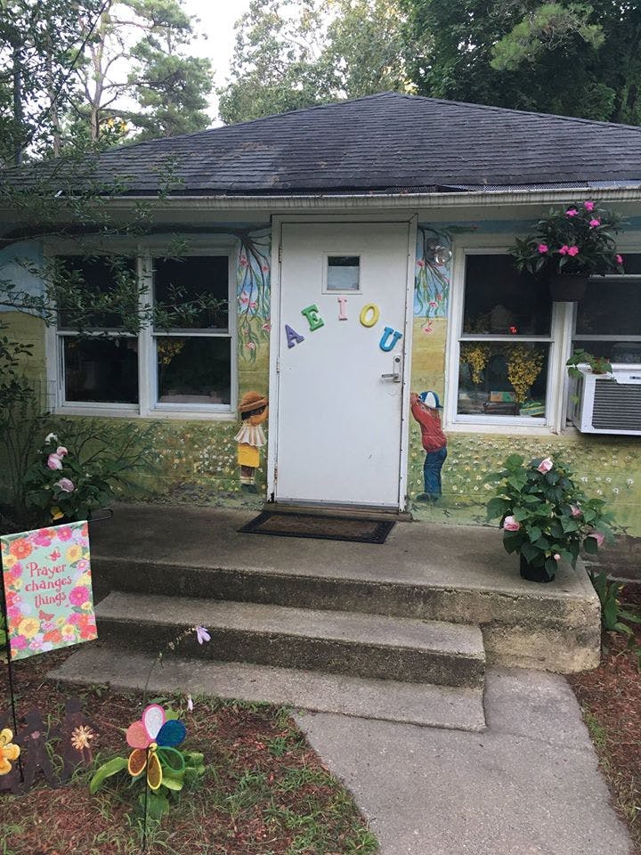Front of a building with a white door decorated with colorful letters A E I O U