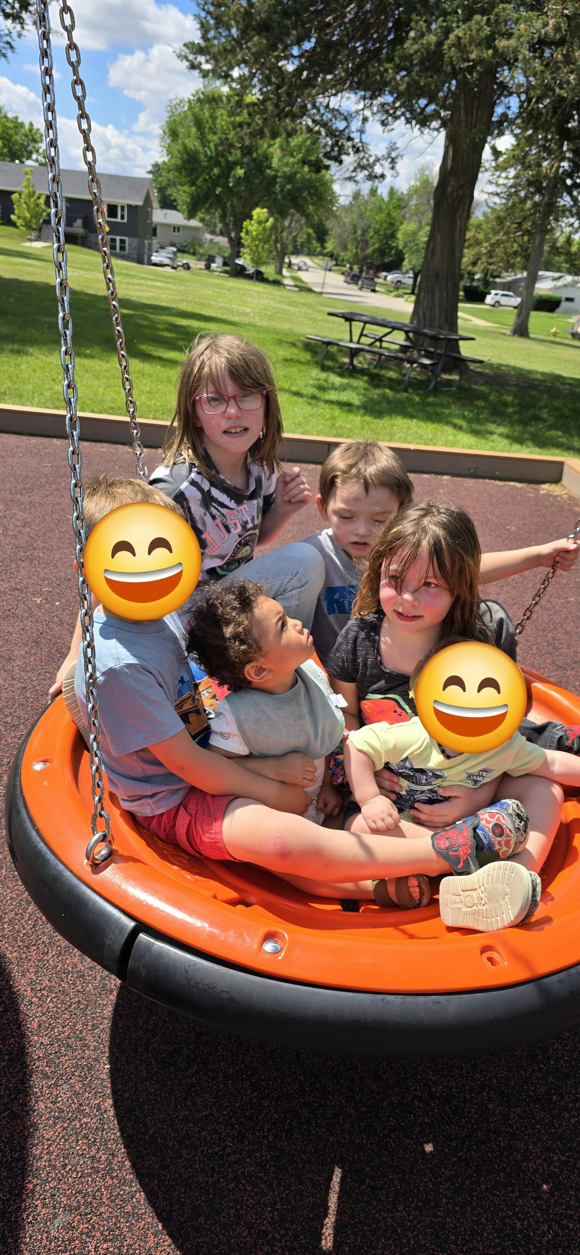 Group of children sitting together on a disc swing at a playground