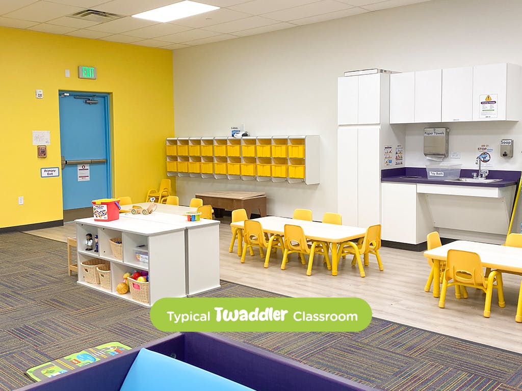 Classroom with small tables and chairs, storage cubbies, and a sink area