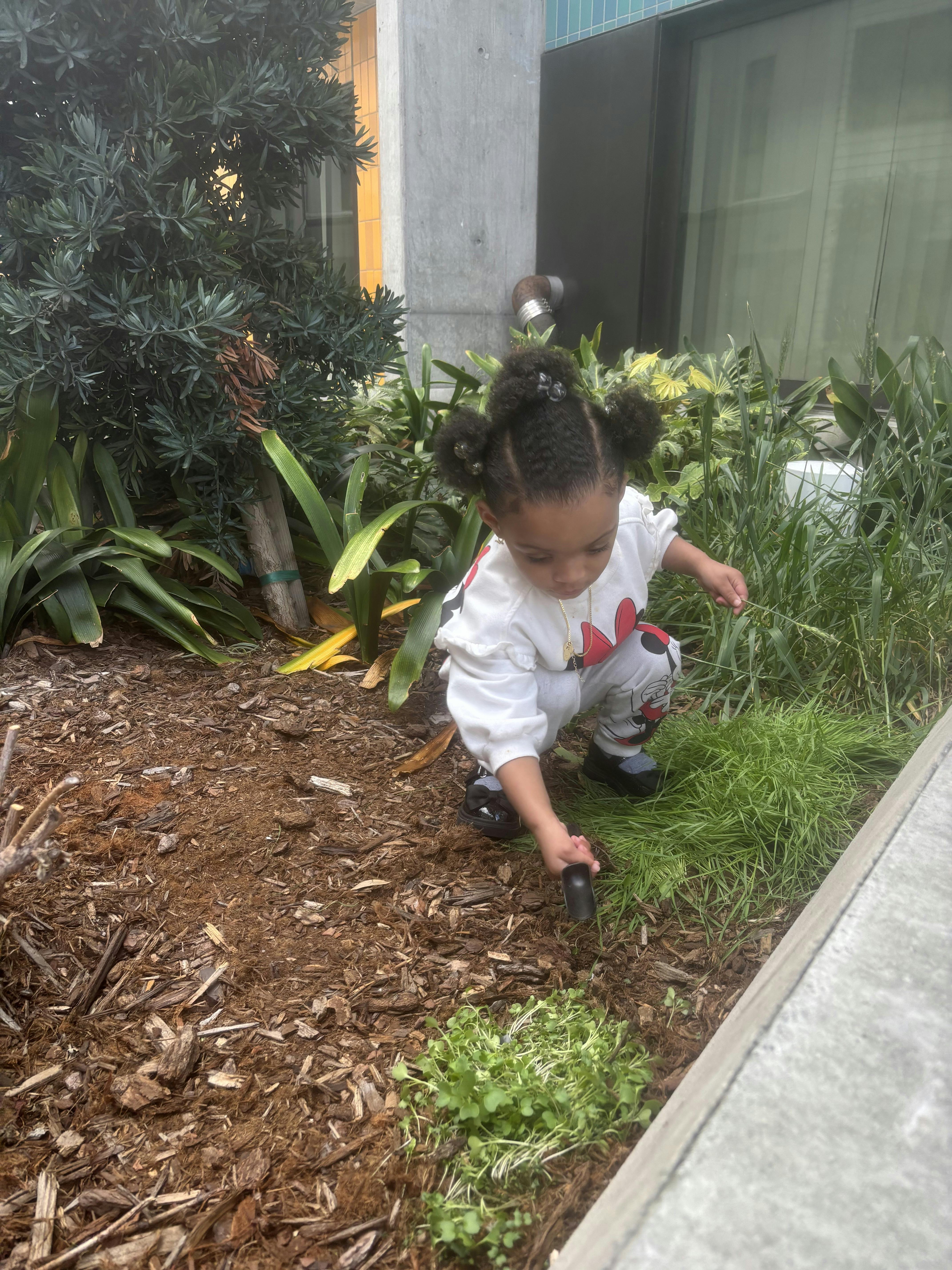 Child crouching and digging in a garden bed