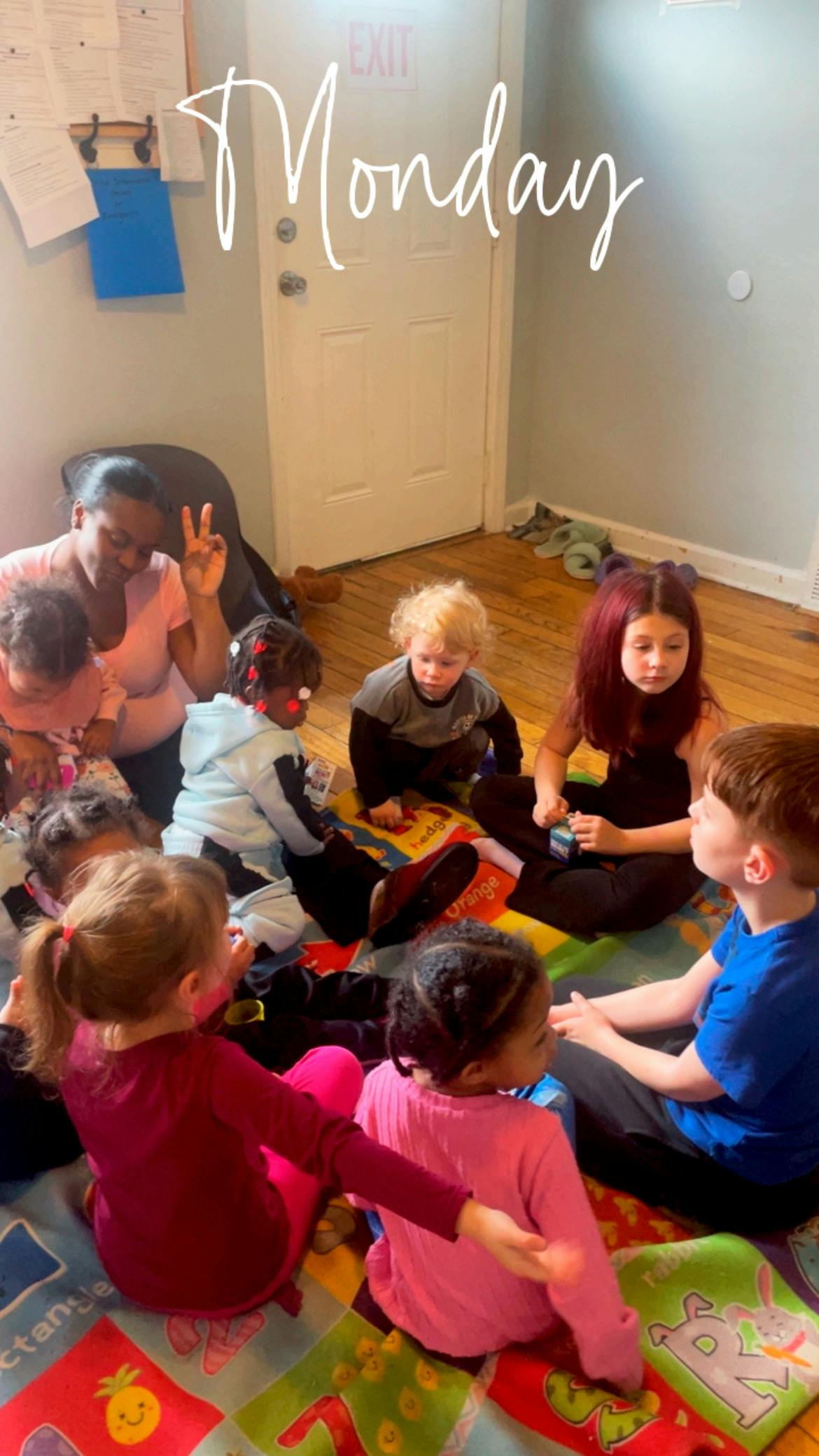 Group of children and a person sitting on a play mat on the floor