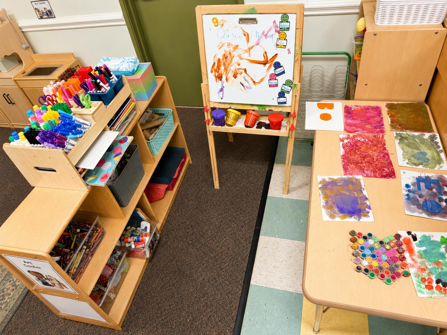 Art supplies and paintings on shelves and tables in a classroom