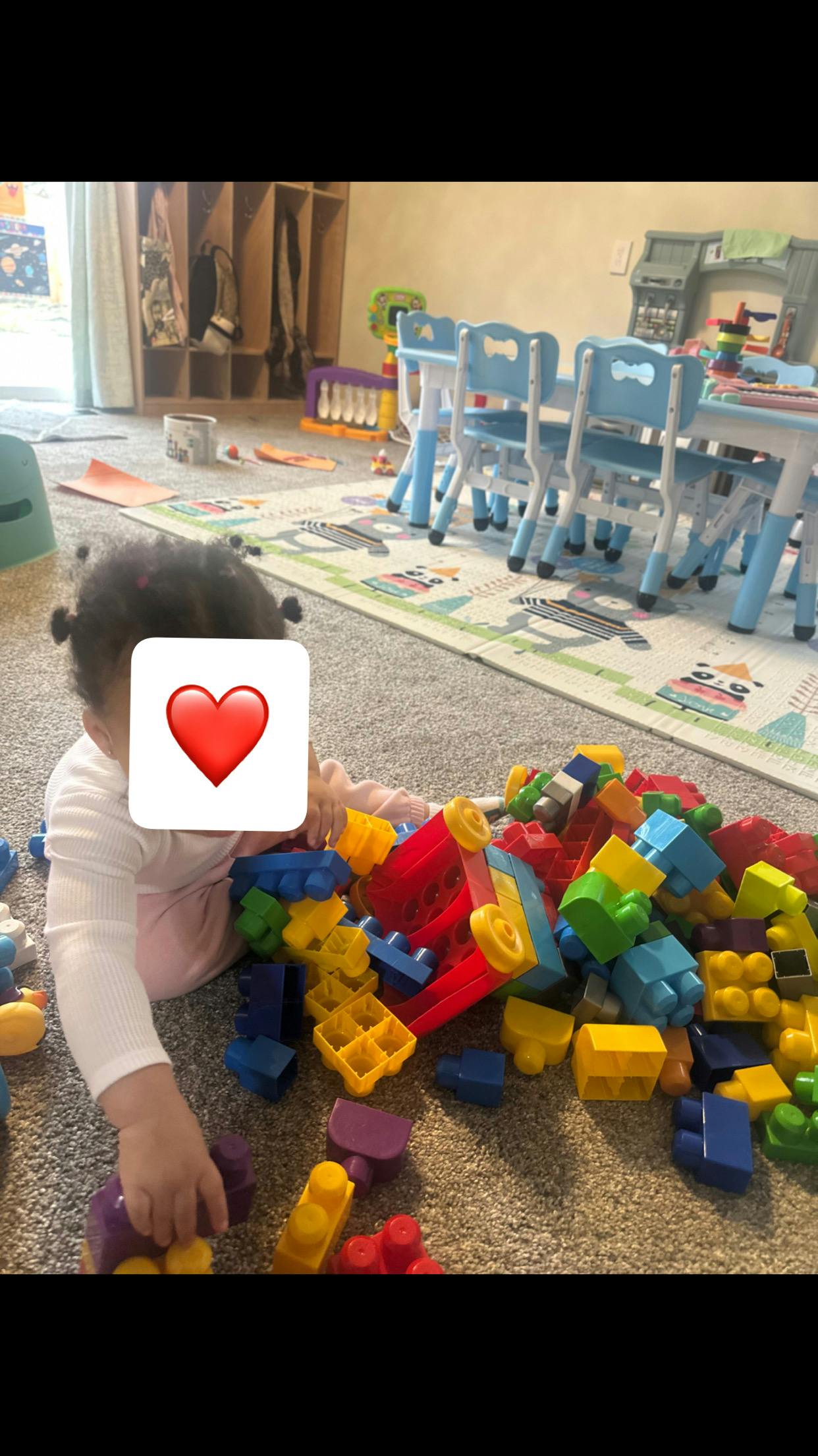 Child playing with colorful building blocks on a carpeted floor