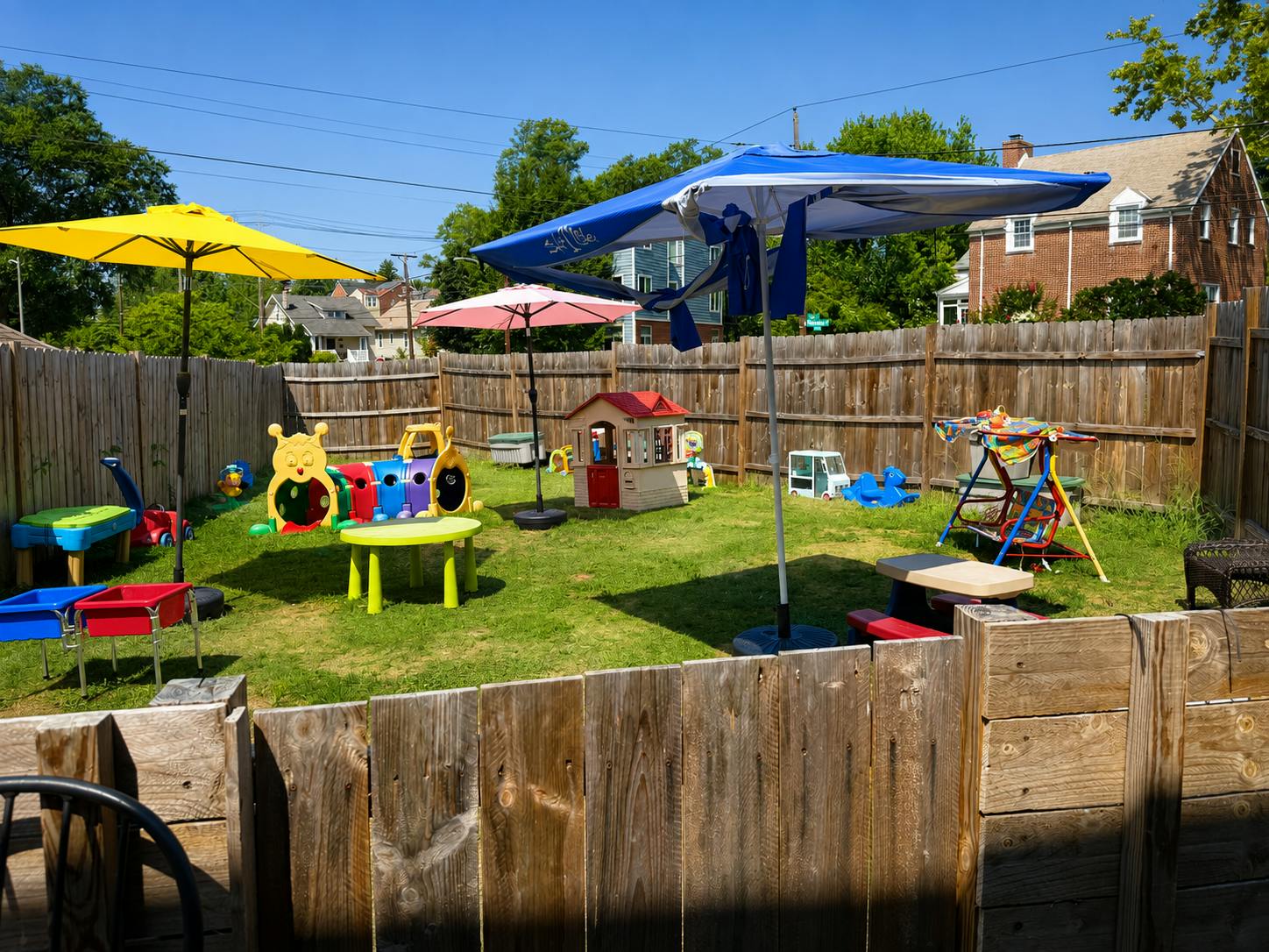Backyard play area with toy structures and umbrellas