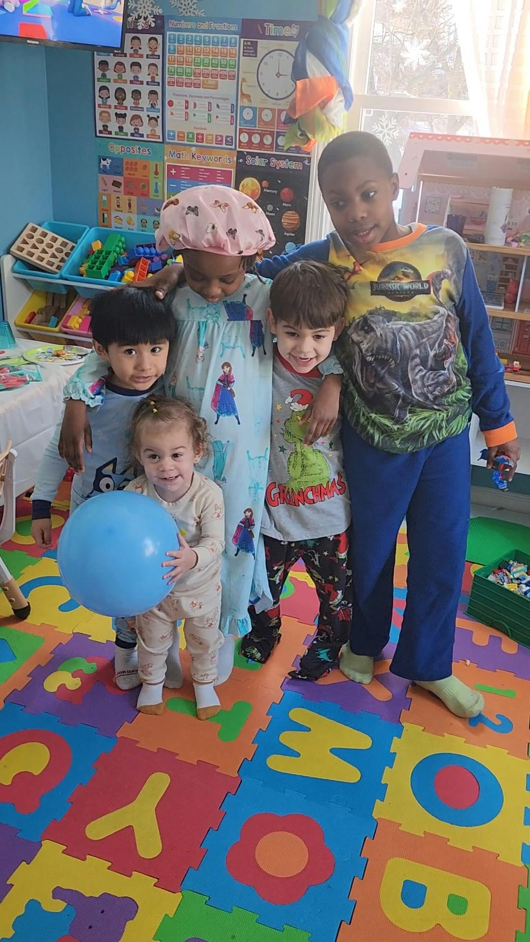 Five children in pajamas standing together in a room