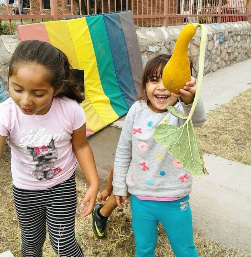 Two children, one holding a yellow gourd with a large leaf