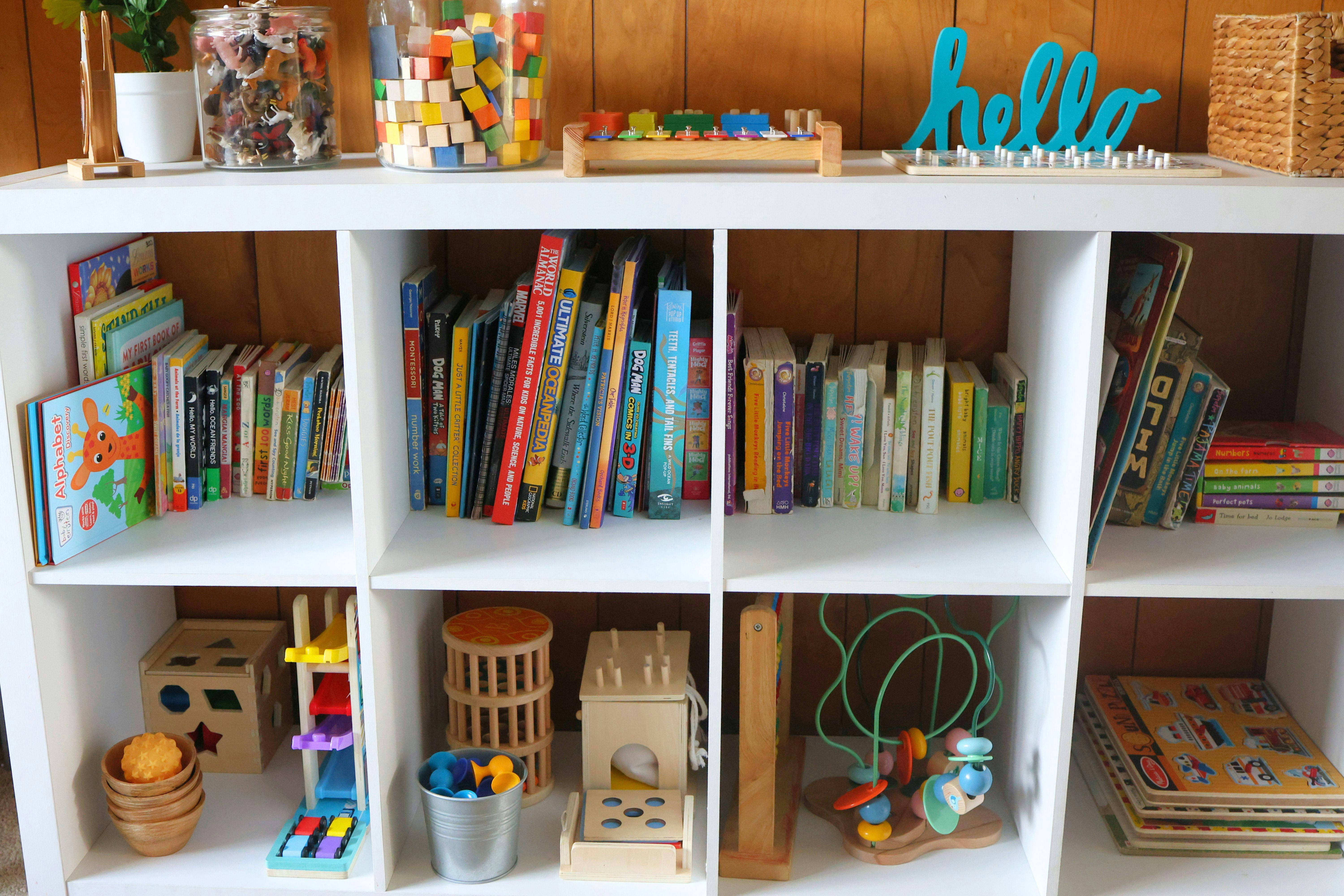 White cubby shelf filled with children's books and toys