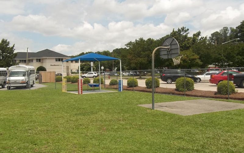 Basketball hoop next to a fenced area with a blue canopy
