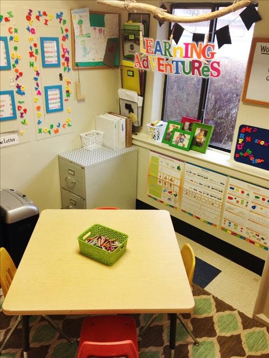 A classroom with a small table, chairs, and colorful decorations