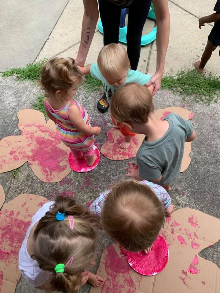 Adult helping children with a painting activity outdoors