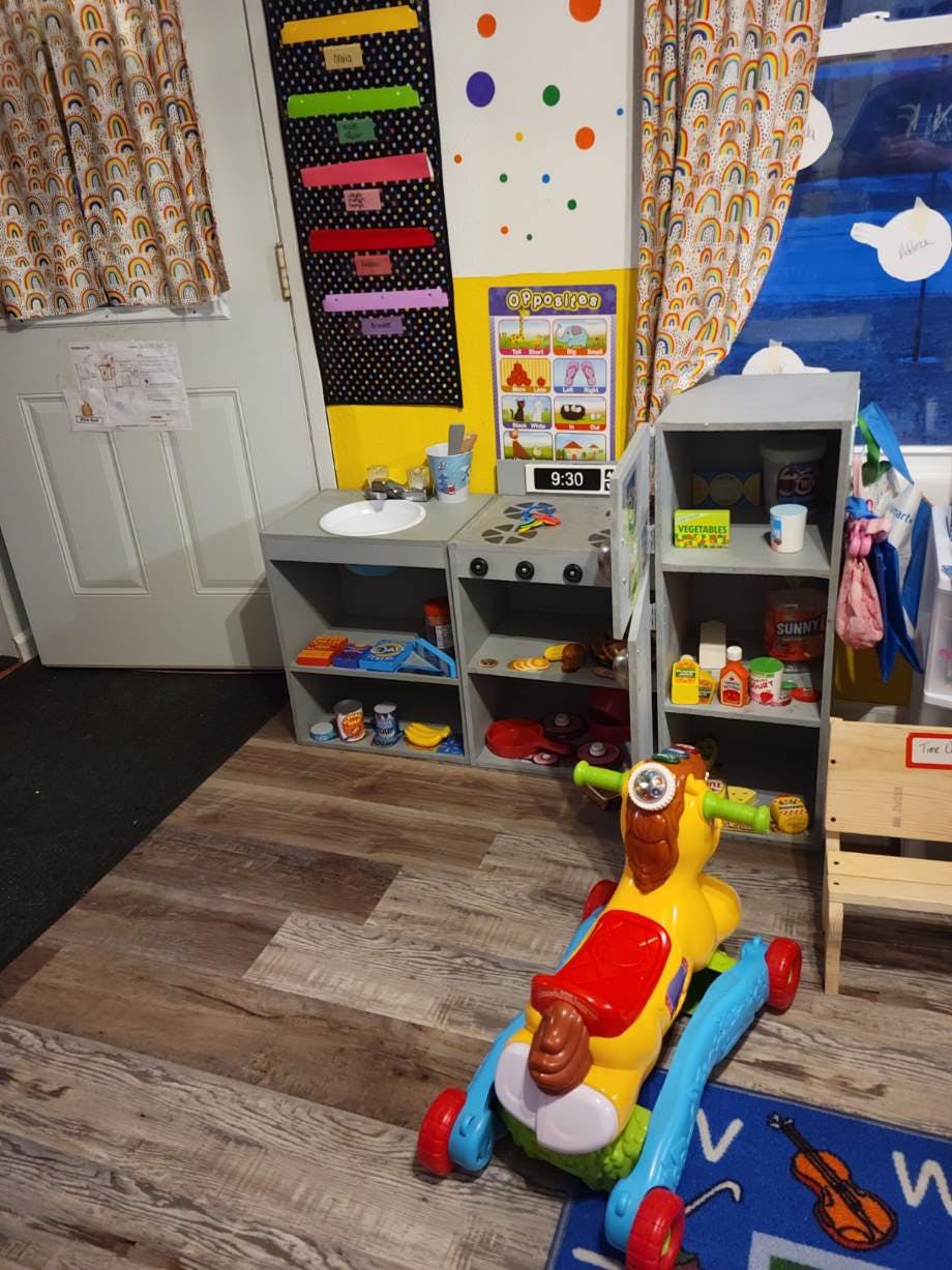 Child's play kitchen with a toy ride-on in the foreground