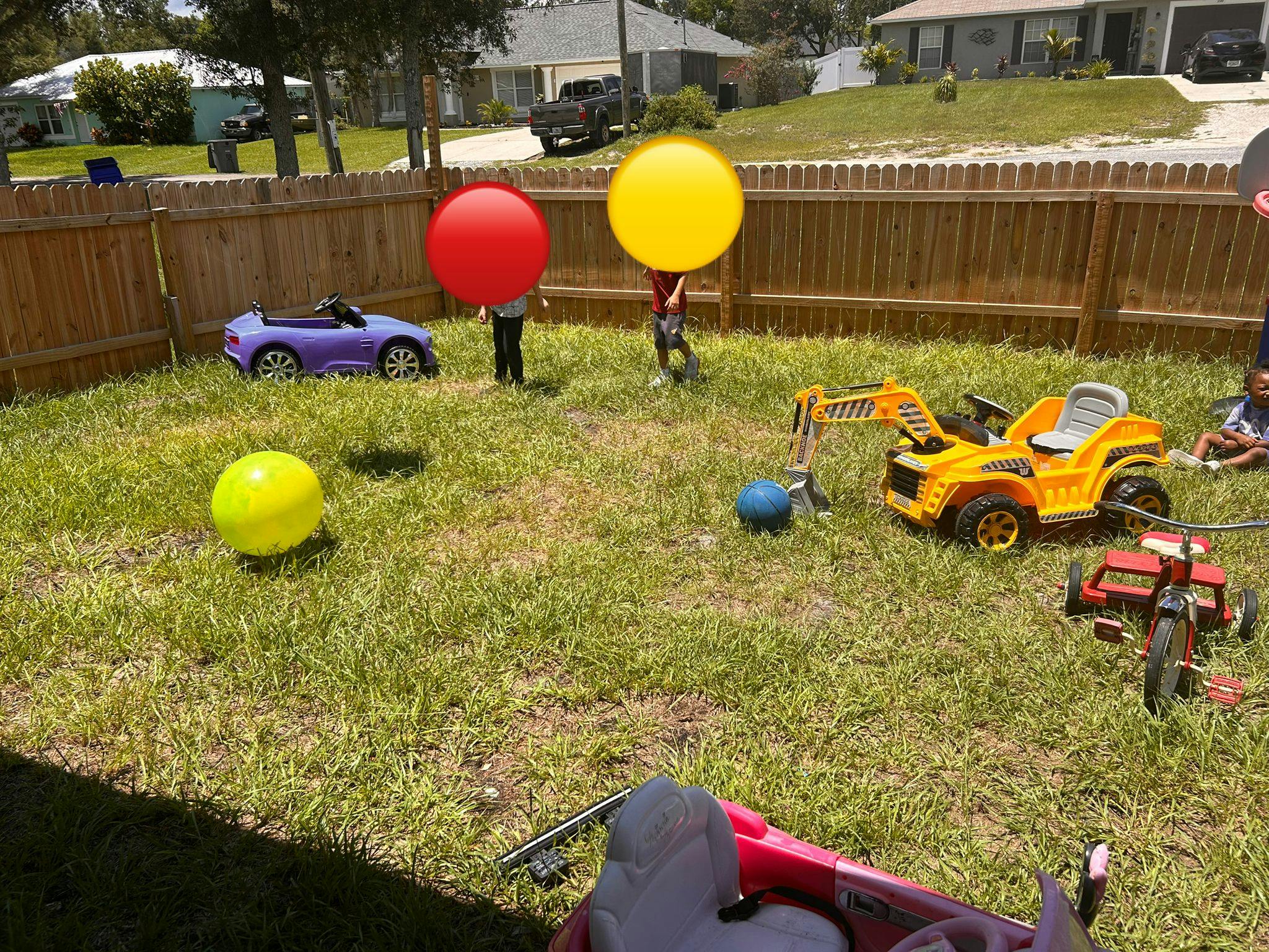 Children playing with toys in a grassy backyard