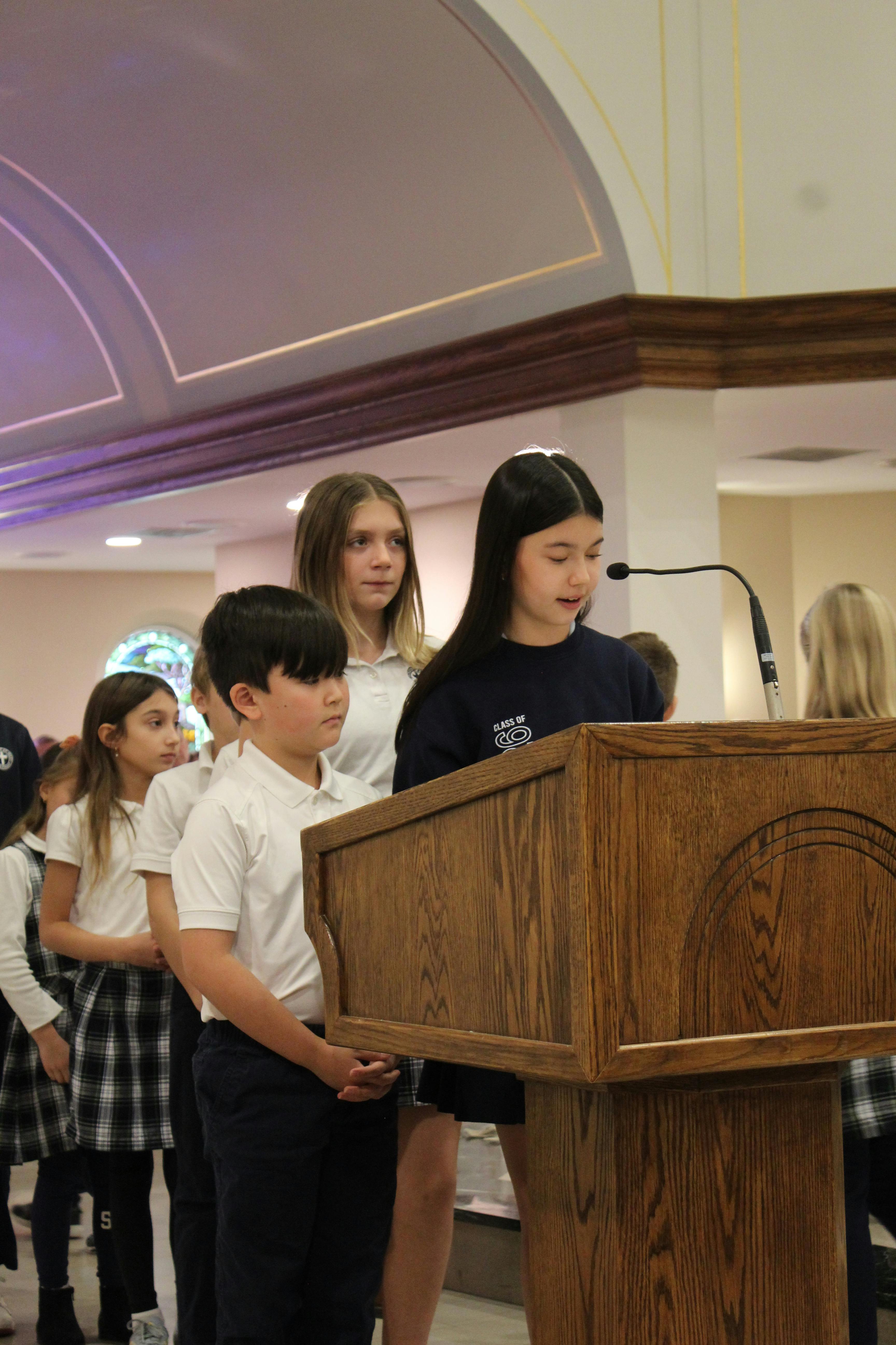 Child speaking into a microphone at a wooden lectern