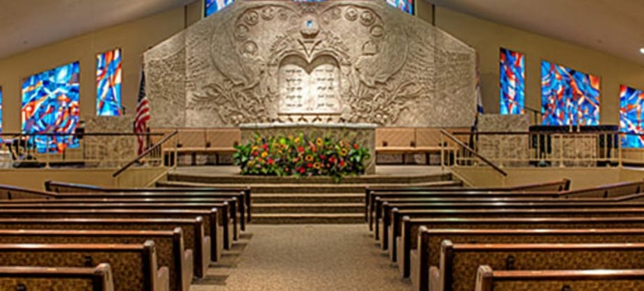 Interior of a synagogue with rows of pews facing an altar with flowers