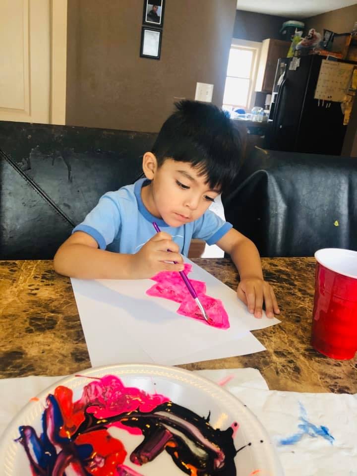 Child painting with pink paint on white paper