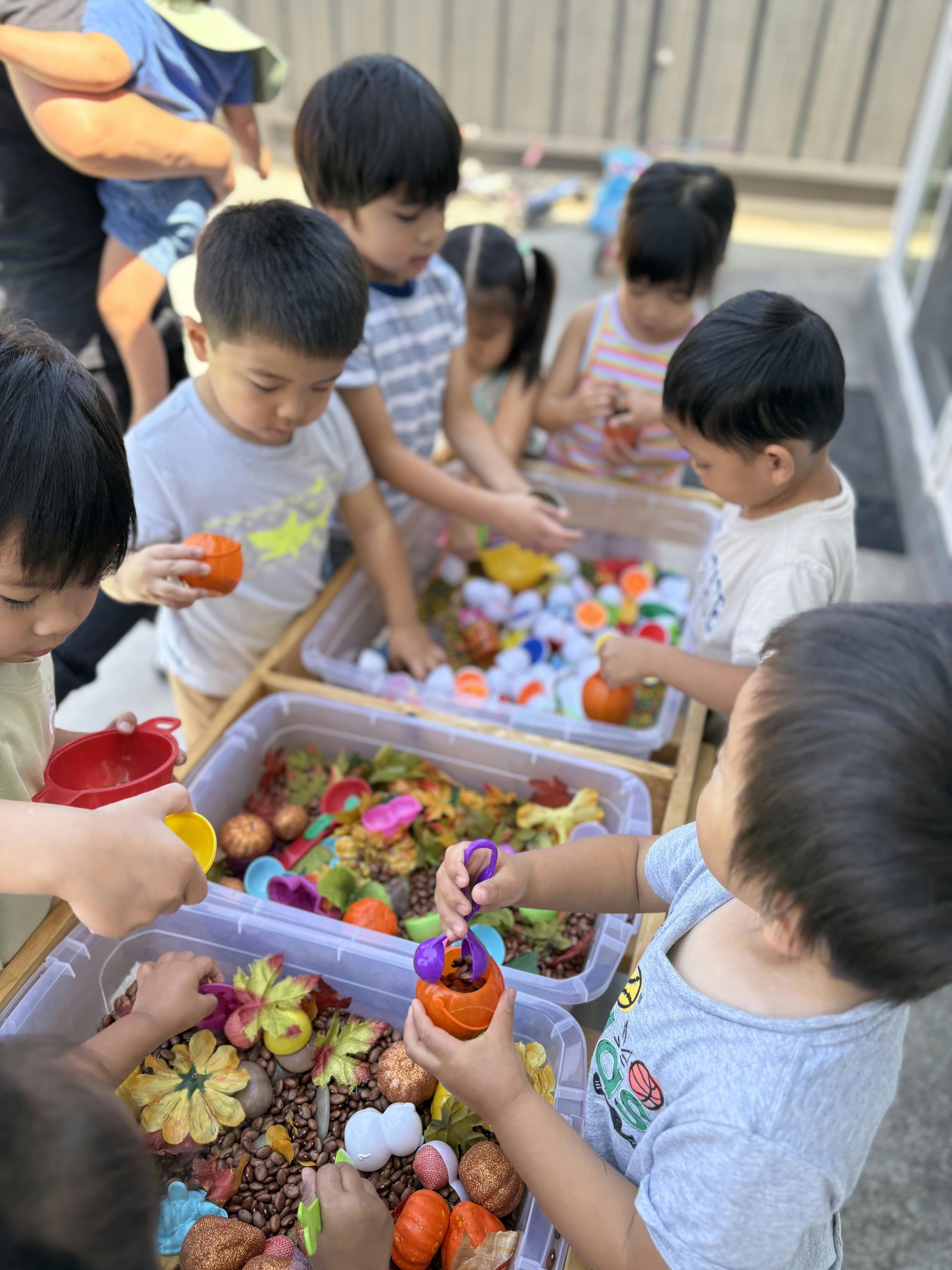 Group of children playing with sensory bins filled with beans and small objects