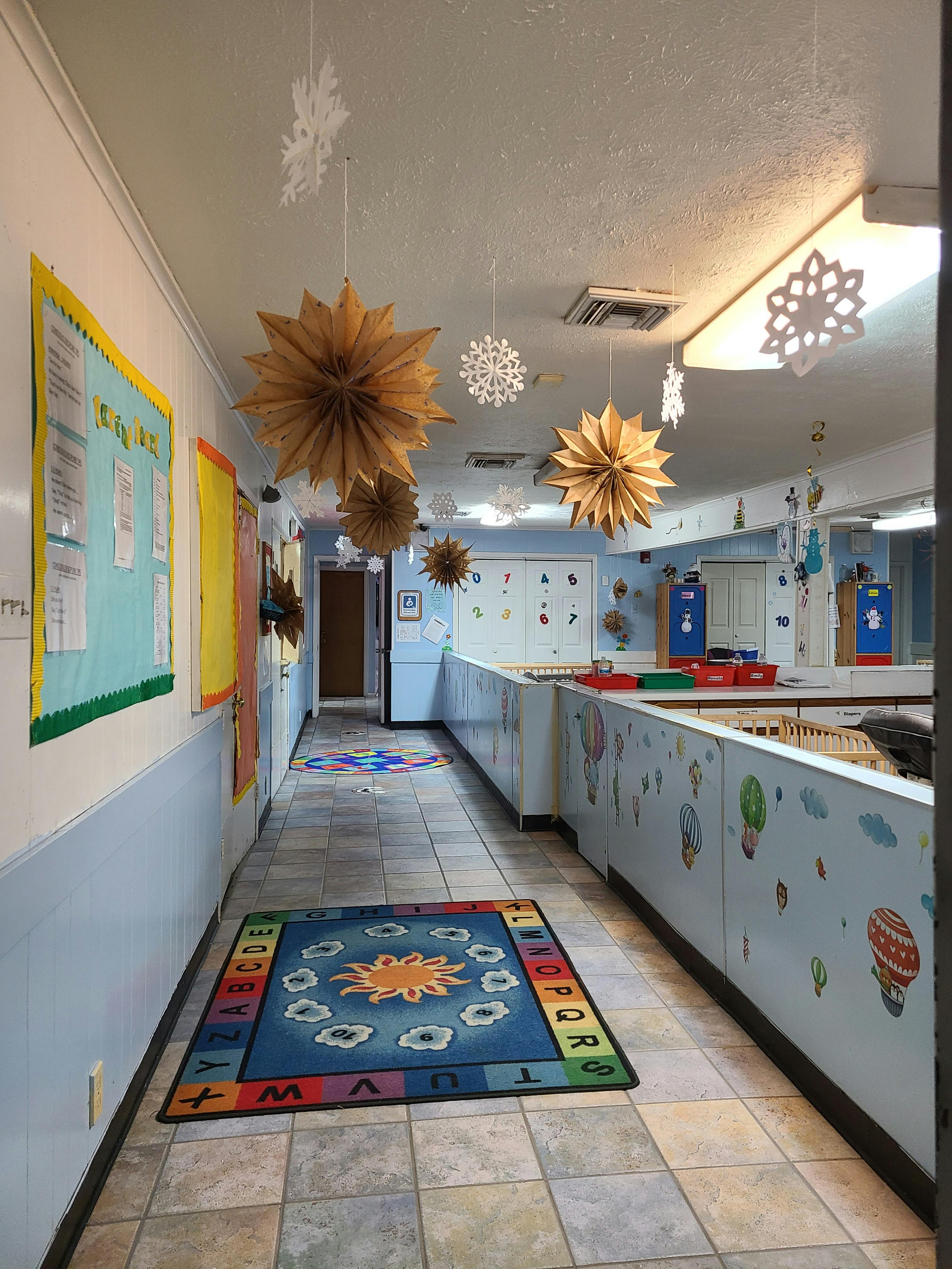 Hallway decorated with paper snowflakes and stars, with a colorful rug on the floor