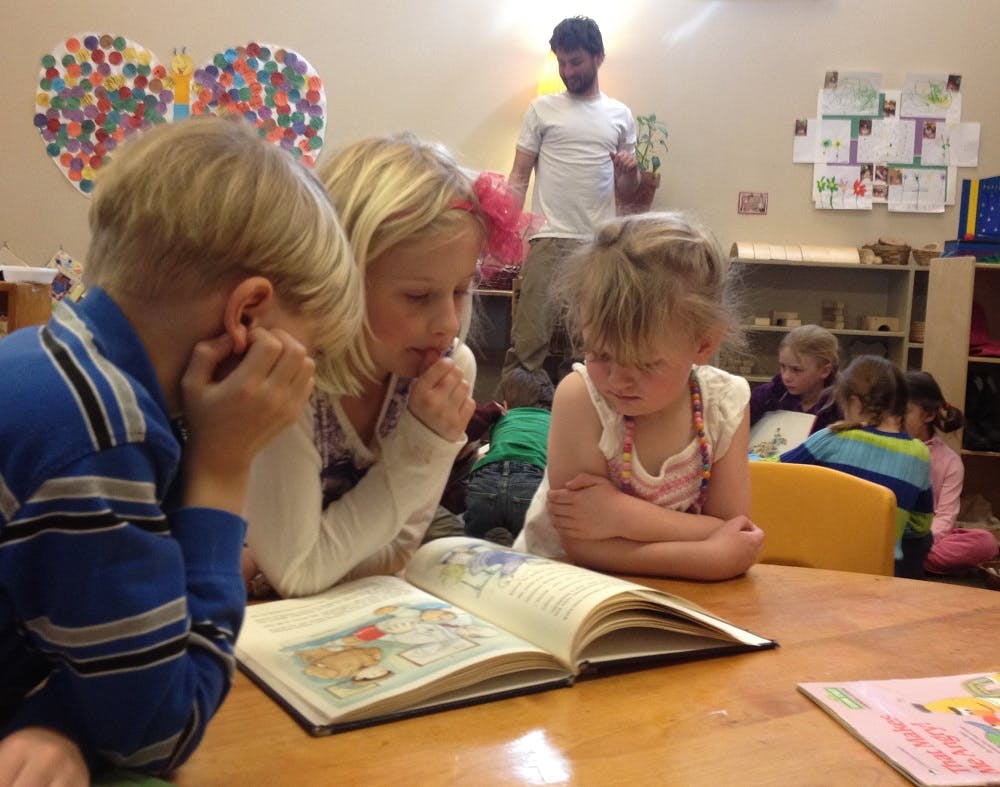 Three children looking at an open book on a table