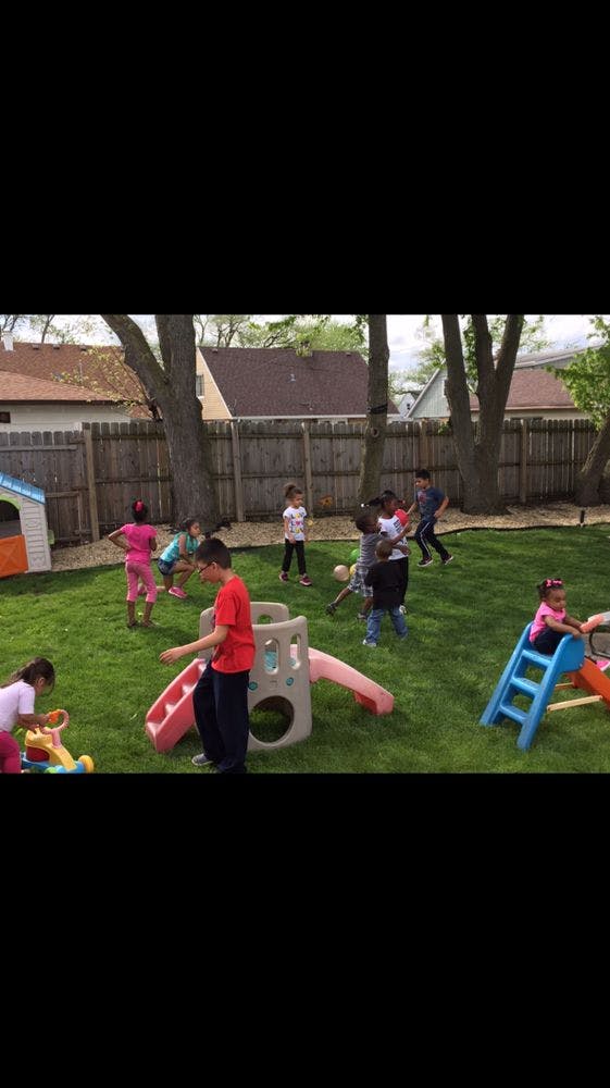Children playing in a grassy backyard with playground equipment