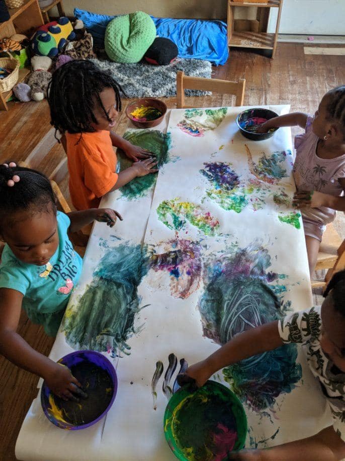 Children finger painting on a large sheet of paper