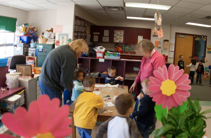 Adults and children gathered around a table in a classroom