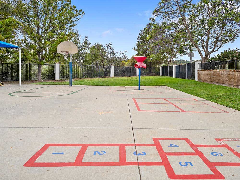 Basketball hoop on a paved court with hopscotch squares