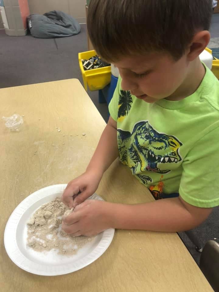Child playing with sand on a paper plate